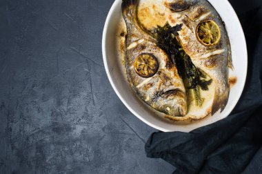 Dorado bir dilim limon ile balık pişmiş. Koyu arka plan, üstten görünüm, metin için yer