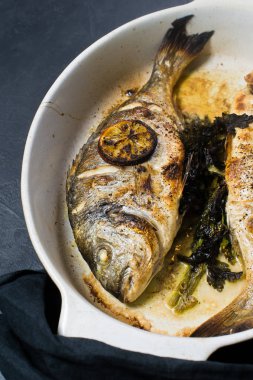 Dorado bir dilim limon ile balık pişmiş. Koyu arka plan, üstten görünüm
