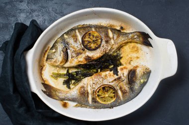 Dorado bir dilim limon ile balık pişmiş. Koyu arka plan, üstten görünüm