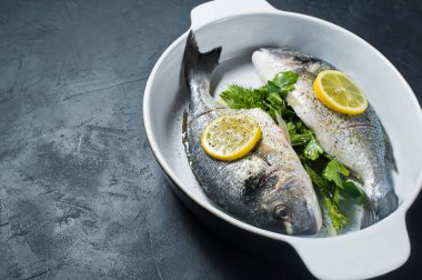 Çiğ Dorado balık Marine zeytin yağı, tuz ve biber, bir dilim limon üstte. Koyu arka plan, üstten görünüm, metin için yer