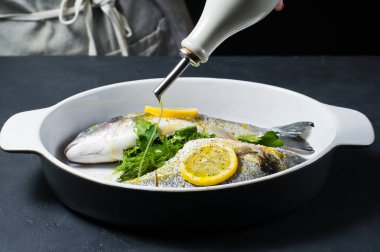 Şef'in balık zeytinyağı ile sulanan Dorado eller. Koyu arka plan, yan görünüm