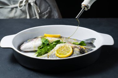 Şef'in balık zeytinyağı ile sulanan Dorado eller. Koyu arka plan, yan görünüm