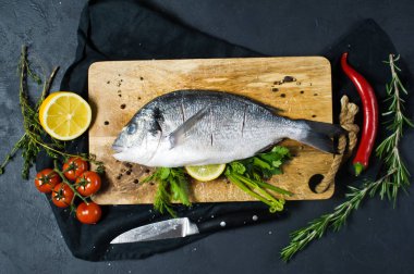 Ahşap Doğrama tahtası doldurulmuş Dorado balık. Madde biberiye, domates, biber, limon, kekik, biber, tuz. Koyu arka plan, üstten görünüm