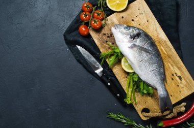 Ahşap Doğrama tahtası doldurulmuş Dorado balık. Madde biberiye, domates, biber, limon, kekik, biber, tuz. Koyu arka plan, üstten görünüm, metin için yer