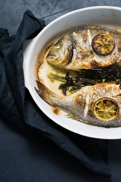 Dorado bir dilim limon ile balık pişmiş. Koyu arka plan, üstten görünüm, yakın çekim
