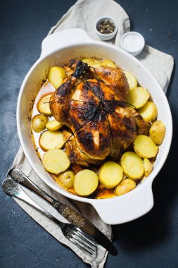 Fırında bütün tavuk patates garnitür ile. Koyu arka plan, üstten görünüm