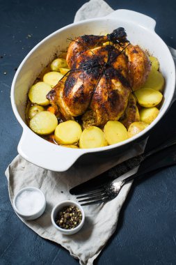 Fırında bütün tavuk patates garnitür ile. Koyu arka plan, üstten görünüm