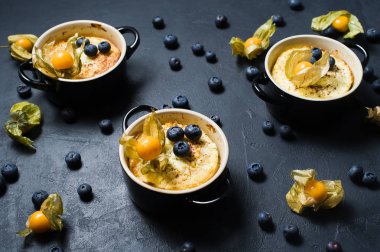 Klasik İngiliz sütlaç. Yaban mersini ve physalis. Koyu arka plan, yan görünüm