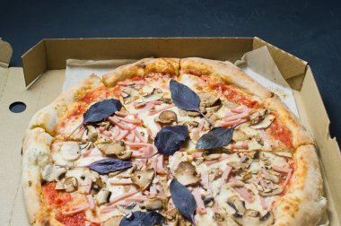 Bir karton kutu, koyu arka plan İtalyan Pizza. Yakın çekim. Yukarıdan görüntüleyin. Pizza teslimatı. Pizza menü.