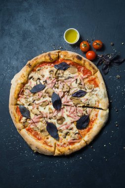 Restoran pizza jambon, mantar ve fesleğen. Koyu arka plan, üstten görünüm