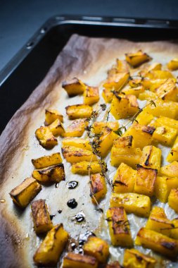 Bir fırın tepsisine fırın balkabağı. Koyu arka plan, üstten görünüm