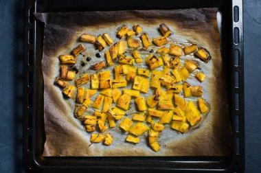 Bir fırın tepsisine fırın balkabağı. Koyu arka plan, üstten görünüm