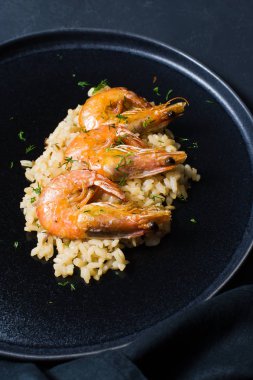 İtalyan risotto ile siyah bir tabak karides. Koyu arka plan, üstten görünüm, yakın çekim