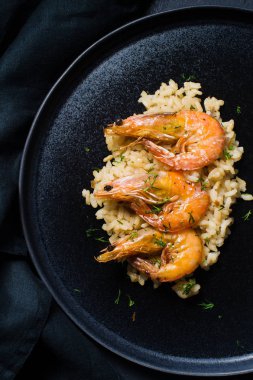 İtalyan risotto ile siyah bir tabak karides. Koyu arka plan, üstten görünüm, yakın çekim