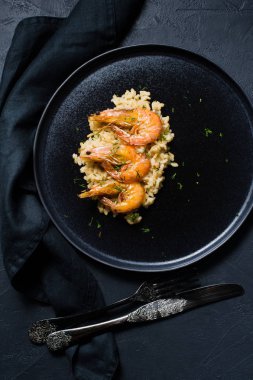 İtalyan risotto ile siyah bir tabak karides. Koyu arka plan, üstten görünüm