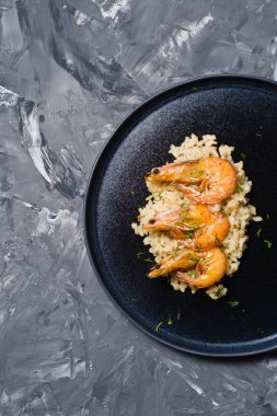İtalyan risotto ile siyah bir tabak karides... Koyu arka plan, üstten görünüm, metin için yer