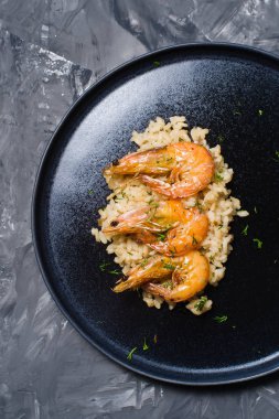 İtalyan risotto ile siyah bir tabak karides... Koyu arka plan, üstten görünüm, metin için yer