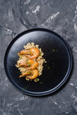 İtalyan risotto ile siyah bir tabak karides... Koyu arka plan, üstten görünüm, metin için yer