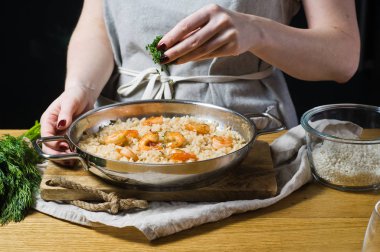 Şef İtalyan risotto pişmiş otlar sprinkles. Karides, beyaz şarap, pirinç, soğan, kekik, sarımsak. Koyu arka plan, yan görünüm