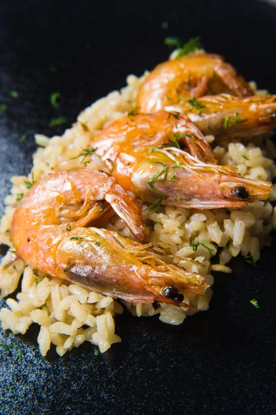 Italian risotto with shrimp on a black plate. Dark background, top view, close up