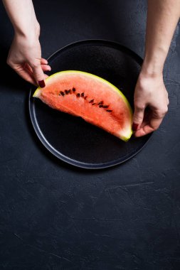 Bir dilim karpuz holding eller. Koyu arka plan, üstten görünüm