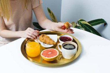 Kruvasan ve kahve ile Fransız kahvaltı. Kadınların elleri kruvasan kır. Kahve, reçel, kruvasan, portakal suyu, greyfurt, lychee. Üstten Görünüm, beyaz arka plan