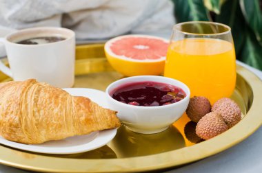 Yatakta, otel hizmeti Fransız kahvaltı. Kahve, reçel, kruvasan, portakal suyu, greyfurt, lychee. Yan görünüm, açık renkli