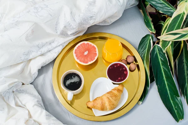 Classic Breakfast in bed, hotel service. Coffee, jam, croissant, orange juice, grapefruit, lychee. Top view, light background