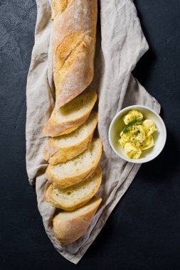Dilimlenmiş Fransız baget ve tereyağı. Siyah arka plan, üstten görünüm