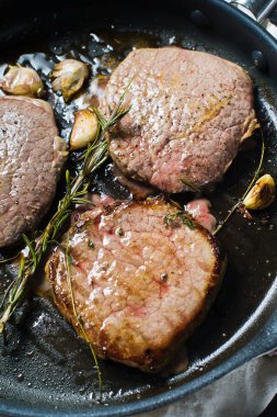 Üç fileto biftek tavada pişirme. Üstten Görünüm, siyah arka plan, kapat