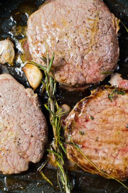 Dana biftek bonfile tavada pişirme. Üstten Görünüm, siyah arka plan, kapat