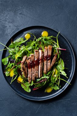 Dana bonfile, roka ve siyah bir tabak pazı salatası. Üstten Görünüm, siyah arka plan