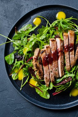 Dana bonfile, roka ve siyah bir tabak pazı salatası. Üstten Görünüm, siyah arka plan