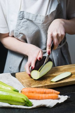 Elinde Şef ahşap kesme tahtası üzerinde patlıcan dilim. Yan görünüm, siyah arka plan, kapat