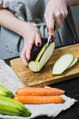 Elinde Şef ahşap kesme tahtası üzerinde patlıcan dilim. Yan görünüm, siyah arka plan, kapat