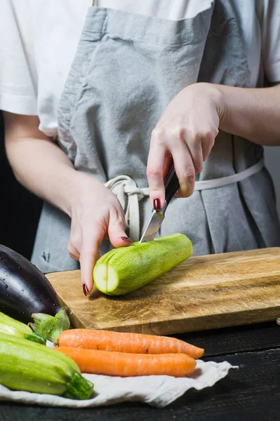 Eller Şef bir Ahşap doğrama tahtası üzerinde kabak kesti. Yan görünüm, siyah arka plan, kapat