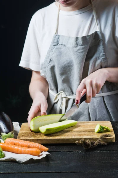 Eller Şef bir Ahşap doğrama tahtası üzerinde kabak kesti. Yan görünüm, siyah arka plan, kapat