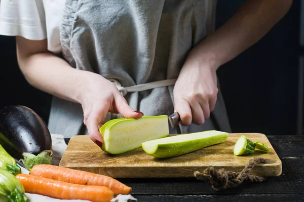 Eller Şef bir Ahşap doğrama tahtası üzerinde kabak kesti. Yan görünüm, siyah arka plan, kapat