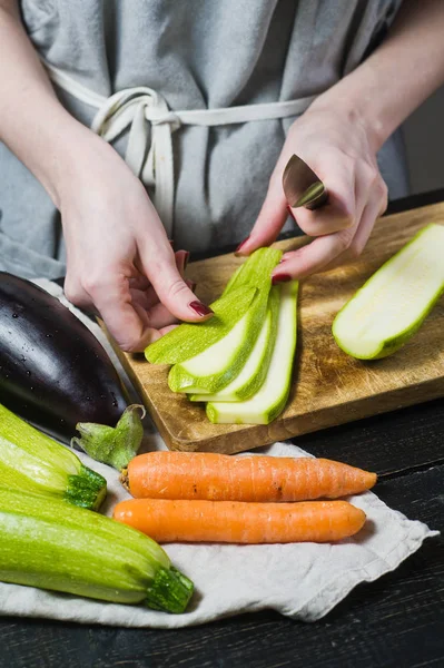 Eller Şef bir Ahşap doğrama tahtası üzerinde kabak kesti. Yan görünüm, siyah arka plan, kapat