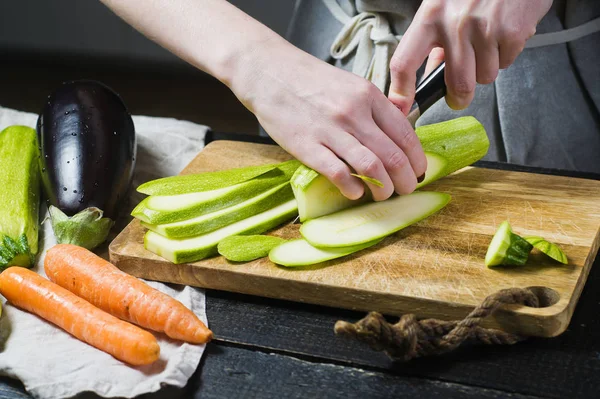 Eller Şef bir Ahşap doğrama tahtası üzerinde kabak kesti. Yan görünüm, siyah arka plan, kapat