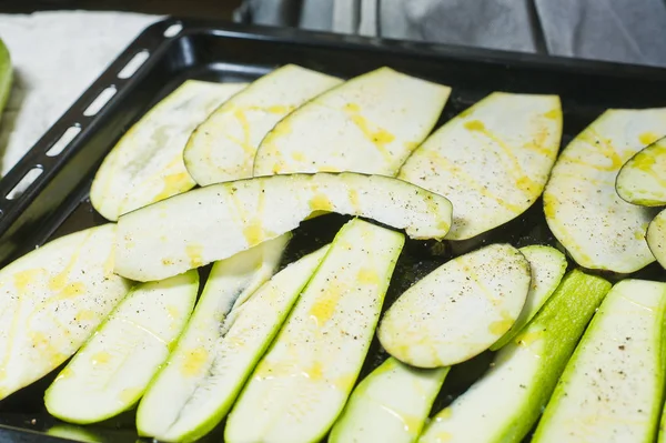 Şef zeytinyağı dilimlenmiş patlıcan dökülen. Yan görünüm, siyah arka plan, kapat