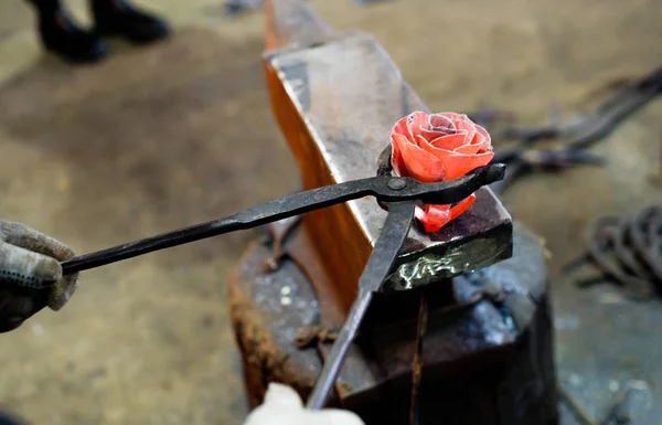 Blacksmith forges steel rose on the anvil