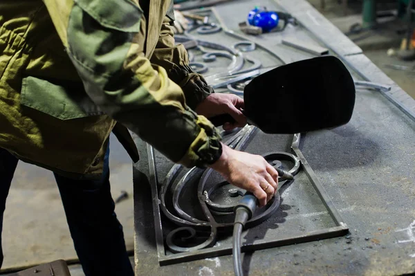 Blacksmith in work clothes is in the forge