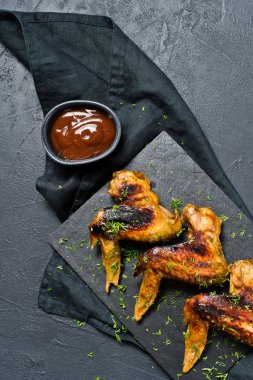 Barbekü tavuk kanatları. Siyah arka plan, üstten görünüm