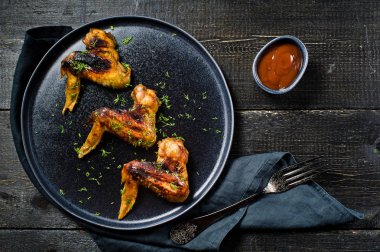 Tavuk kanadı Barbekü siyah plaka üzerinde. Siyah ahşap arka plan, yan görünüm