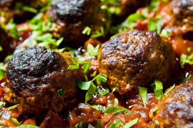 İsveç köftesi domates soslu bir pişirme çanağı içinde. Siyah arka plan, üstten görünüm, yakın çekim