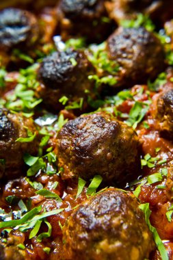 İsveç köftesi domates soslu bir pişirme çanağı içinde. Siyah arka plan, üstten görünüm, yakın çekim