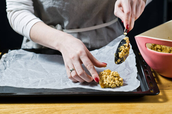 Шеф-повар готовит печенье, разбрасывает тесто на подносы. Вид сбоку, черный фон, кухня
.