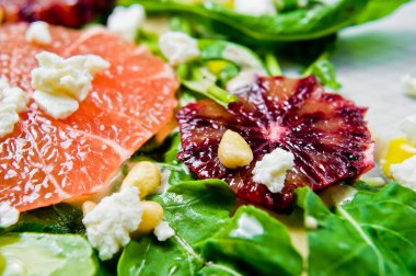 Roka, greyfurt, kırmızı portakal, fındık ve soya peyniri vejetaryen salatası. Gri arka plan, üstten görünüm, yakın çekim