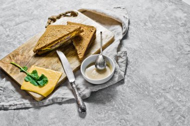 Peynir dönüş, siyah ekmek, hindi eti ve roka ile tost. Gri arka plan, üstten görünüm, metin için yer